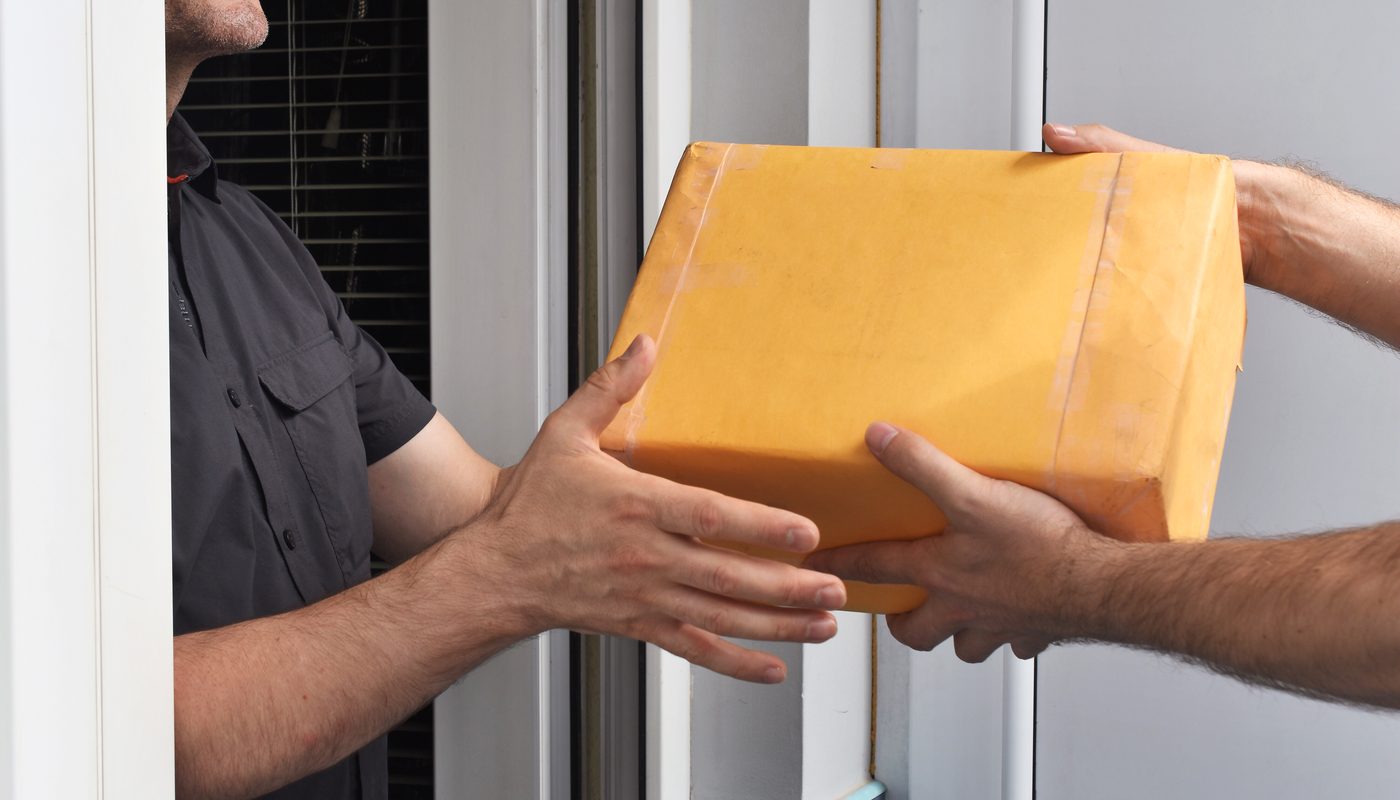 Uniformed handler collecting a sealed parcel at a doorstep for TransBaggage