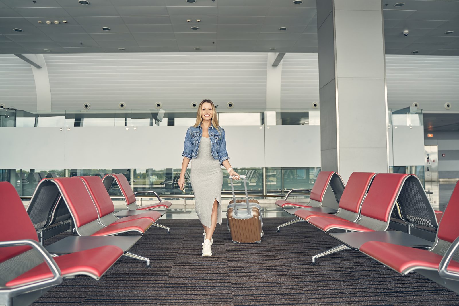 Traveller walking through a London airport terminal pulling a suitcase after a TransBaggage collection